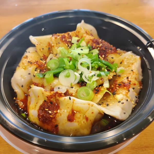 Senzu Noodle Bar's Japanese dumplings, drizzled with chili oil, sesame seeds, and fresh green onions.