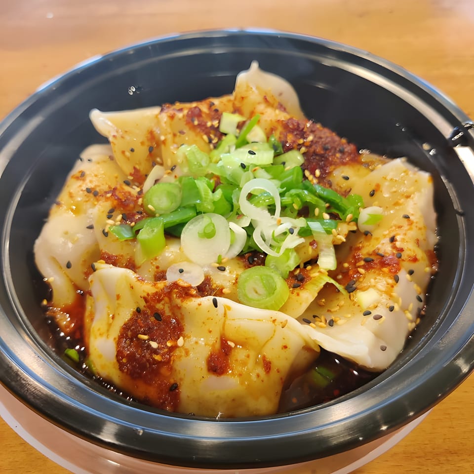 Senzu Noodle Bar's Japanese dumplings, drizzled with chili oil, sesame seeds, and fresh green onions.